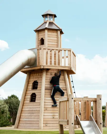 Een avonturier beklimt de houten vuurtoren in de speeltuin