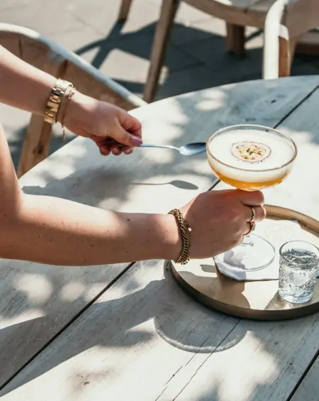 Gastvrij genieten op De Zeeuwse Kust, een perfect geserveerde passievrucht martini wordt op het zonnige terras neergezet