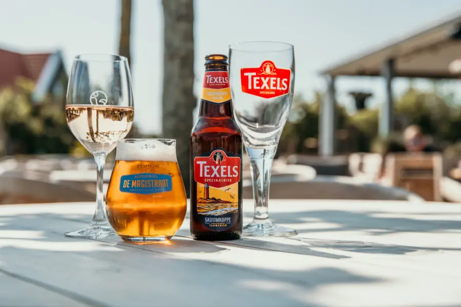 Terrasdrankjes in de zon, een fles Texels Skuumkoppe, een fris glas witte wijn en een ontspannen sfeer