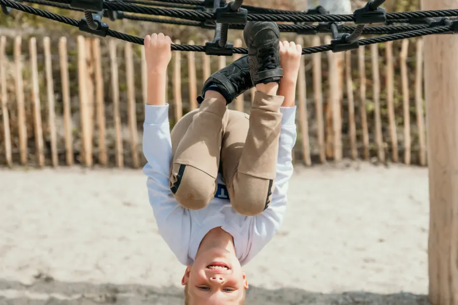 Jongen klimt en speelt in de nieuwe houten buitenspeeltuin dichtbij het strand