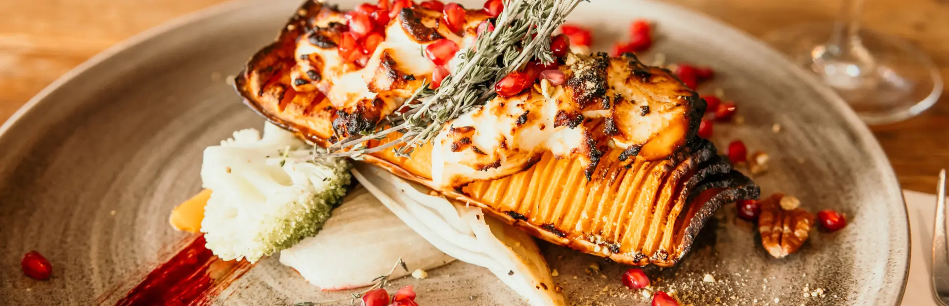 Fijnproeversgerecht met gegrilde pompoen granaatappel en kruiden geserveerd in het restaurant van Strandpark De Zeeuwse Kust op een sfeervol bord