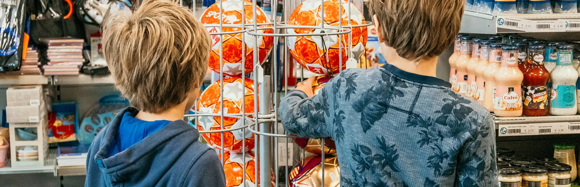 Twee jongens bekijken voetballen in de winkel van Strandpark De Zeeuwse Kust