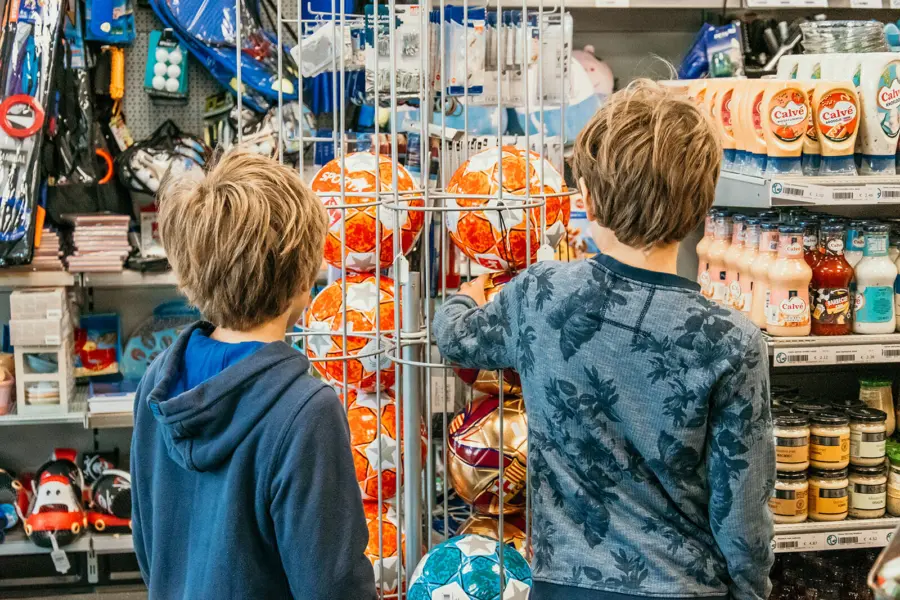 Twee jongens bekijken voetballen in de winkel van Strandpark De Zeeuwse Kust